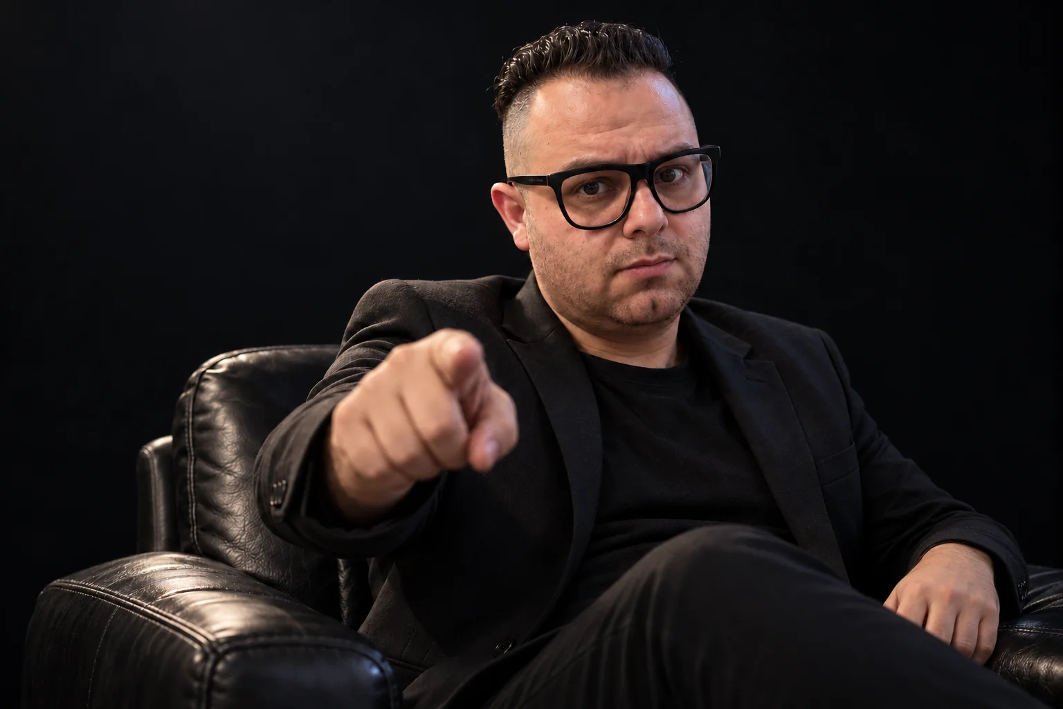 Retrato editorial de Fellipe Antequera sentado em poltrona, apontando para a lente